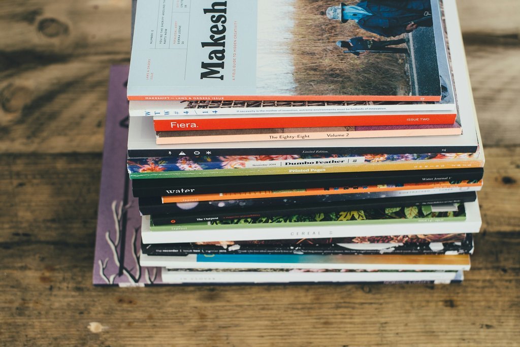 A person organizes stacks of printed publications in an industrial warehouse setting.